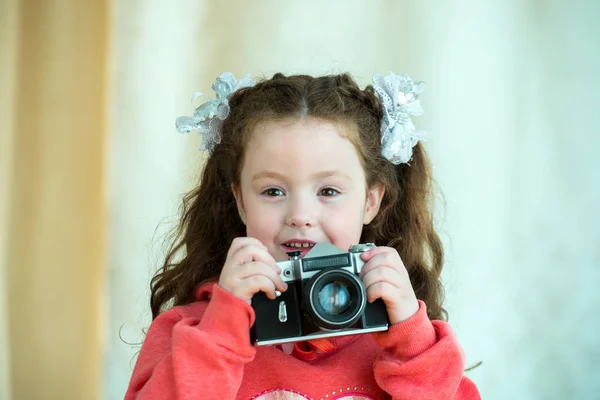 Liten flicka med Vintage kamera på ljus bakgrund. Leende söt unge flicka 4-5 år gammal — Stockfoto