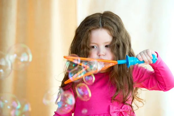 Liten flicka med långt hår blåser bubblor — Stockfoto