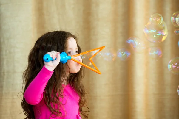 Menina com cabelo longo soprando bolhas — Fotografia de Stock