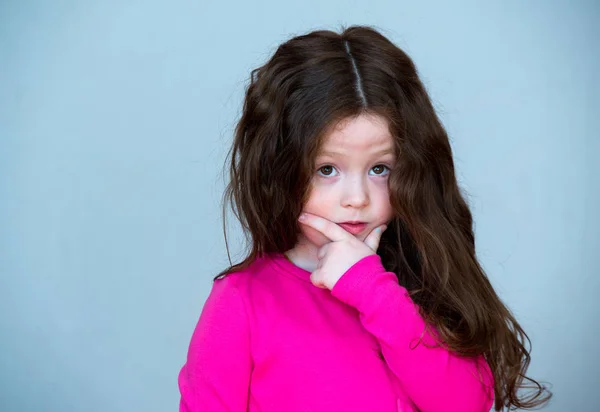 Menina bonita 4-5 anos de idade com cabelo castanho longo. A criança está perplexa. Em pensamento . — Fotografia de Stock