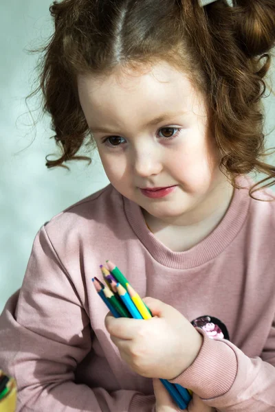 Porträtt av liten flicka som håller färgade pennor och tittar på kamera — Stockfoto