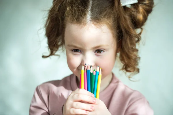 Retrato de menina segurando lápis coloridos e olhando para a câmera — Fotografia de Stock