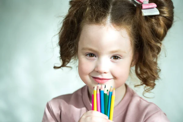 Retrato de menina segurando lápis coloridos e olhando para a câmera — Fotografia de Stock