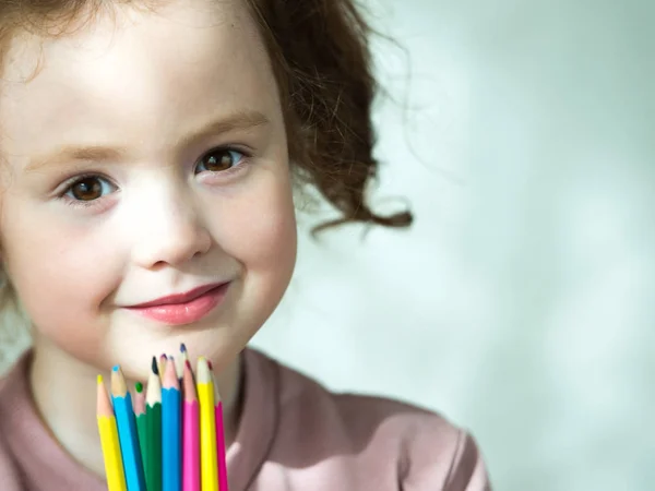 Porträtt av liten flicka som håller färgade pennor och tittar på kamera — Stockfoto