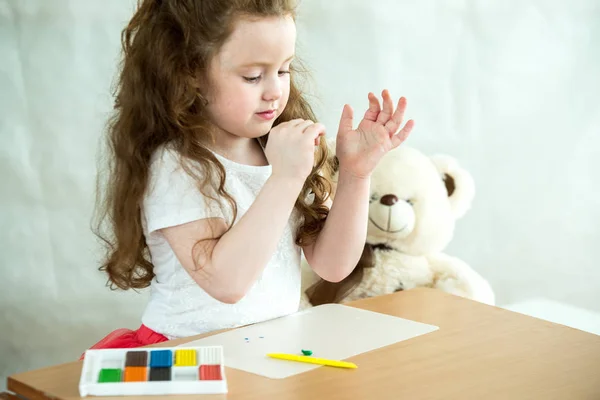 En liten flicka lär sig att använda färgglada spela degen. Närbild. — Stockfoto