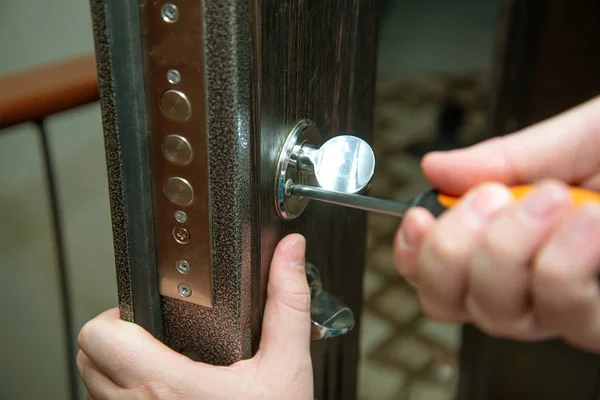 Adam kapıyı tornavidayla onariyor. Kapı kilidi tamiri