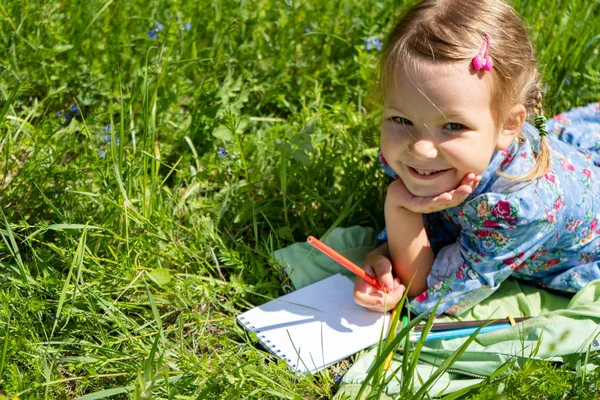 Pequena menina feliz 4-5 anos de idade está na grama verde. Pintura uma menina engraçada . — Fotografia de Stock