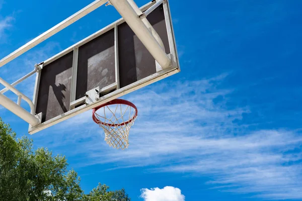 Basketbalový nalepených s kroužkem na ulici a modrou oblohou — Stock fotografie