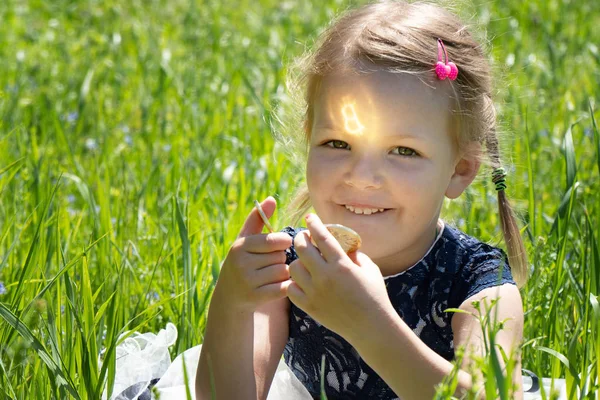 Liten flicka som innehar en Bitcoin kryptovaluta mynt i händerna. Ett barn leker med guldmynt som sitter på gräset. — Stockfoto