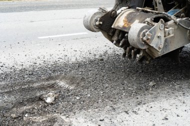 Yol frezeleme makinesi eski asfalt keser. Yol tamiri. Yol yüzeyinin yok edilmesi. Kesici bir asfalt tabakası keser. Taş parçaları birbirinden ayrı uçar. Close