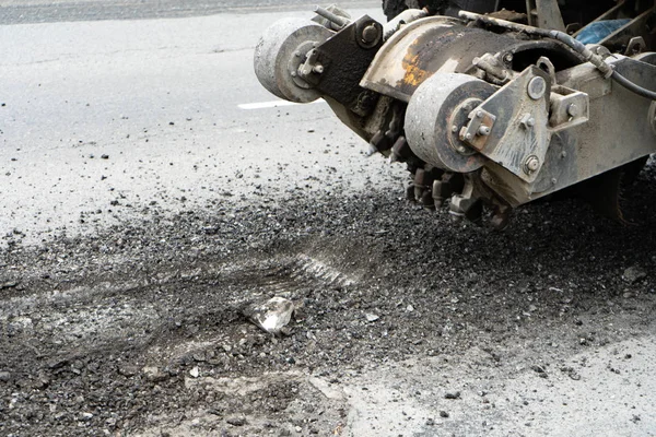 Yol frezeleme makinesi eski asfalt keser. Yol tamiri. Yol yüzeyinin yok edilmesi. Kesici bir asfalt tabakası keser. Taş parçaları birbirinden ayrı uçar. Close