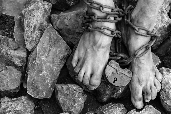돌 가운데 노예의 다리에 자물쇠가달린 체인. 발목체인. 노예제도의 상징 — 스톡 사진