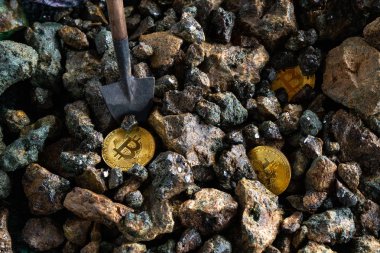 Bir kürek ile taşların bir arka plan üzerinde altın sikke bir bitcoin yığınının üst görünümü yakın çekim. Kripto para madenciliği kavramı