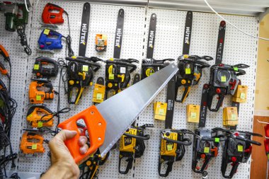 Chelyabinsk Region, Rusya - Haziran 2019. Elektrikli testereli bir rafın arka planına karşı el testeresi. Çeşitli üreticilerin mağaza raflarında yapı aracı. Testereler, elektrikli testereler, fırça çatal