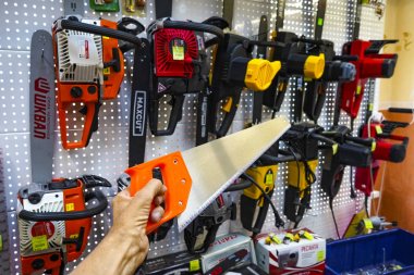 Chelyabinsk Region, Rusya - Haziran 2019. Elektrikli testereli bir rafın arka planına karşı el testeresi. Çeşitli üreticilerin mağaza raflarında yapı aracı. Testereler, elektrikli testereler, fırça çatal