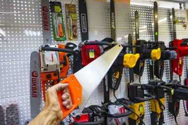 Chelyabinsk Region, Rusya - Haziran 2019. Elektrikli testereli bir rafın arka planına karşı el testeresi. Çeşitli üreticilerin mağaza raflarında yapı aracı. Testereler, elektrikli testereler, fırça çatal