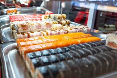 Cam büfede bir sürü suşi rulosu var. Japonya geleneksel gıda.