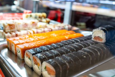 Cam büfede bir sürü suşi rulosu var. Japonya geleneksel gıda.