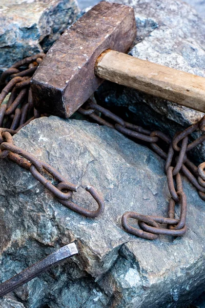 生锈的链子和灰色的石头上的旧锤子。条条条是解放劳动的象征. — 图库照片