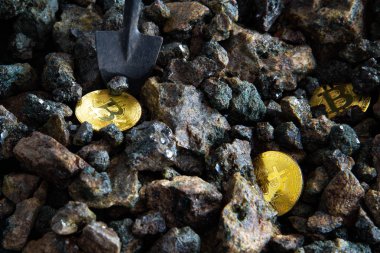 Bir kürek ile taşların bir arka plan üzerinde altın sikke bir bitcoin yığınının üst görünümü yakın çekim. Kripto para madenciliği kavramı