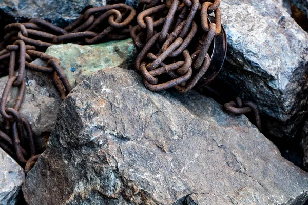 Rusty łańcuch na szare kamienie. Symbol pracy niewolniczej — Zdjęcie stockowe