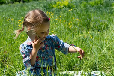 Yeşil çim telefonda konuşan mutlu küçük kız.