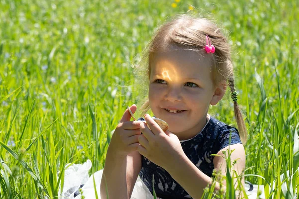 Liten flicka som innehar en Bitcoin kryptovaluta mynt i händerna. Ett barn leker med guldmynt som sitter på gräset. — Stockfoto