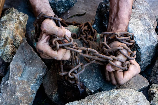 Las manos de un esclavo en un intento de liberación. El símbolo del trabajo esclavo. Manos en cadenas —  Fotos de Stock