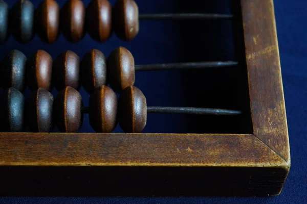 Vintage wooden abacus close up. Counting wooden knuckles. Part of the old end of the abacus on a dark blue background. — Stock Photo, Image