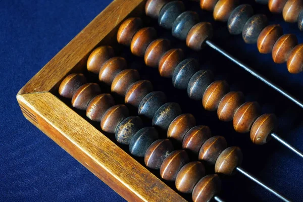 Vintage wooden abacus close up. Counting wooden knuckles. Part of the old end of the abacus on a dark blue background. — Stock Photo, Image