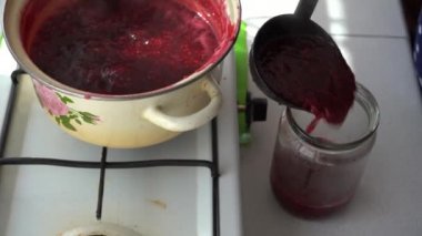 Kadın kavanoza el yapımı dut reçeli koyar. Ahududu reçelini kaynatın. Güneş ışığında canlı renkler.