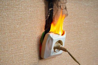 Yanan elektrik kabloları ve elektrik prizi. Hatalı kablolama yangına neden olur. Kötü eski kablolama elektrik prizinde yangına neden olur.