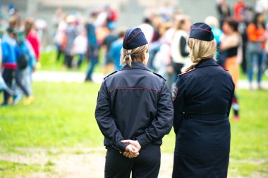Chelyabinsk Region, Rusya - Haziran 2019: Kadın polis memurları kalabalığı izliyor. Üniformalı iki kimliği belirsiz Rus polis kadını, bir çocuk döneminde hukukun üstünlüğünün gözetlendiğini izliyor.