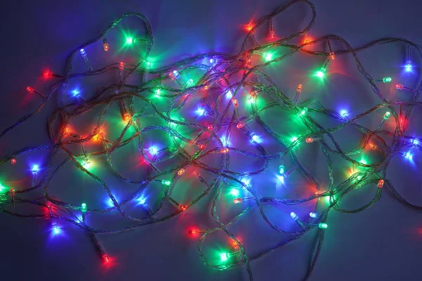 Karácsonyi sokszínű fények. Elektromos LED lámpák véletlenszerűen lefektetett sötét háttér. Dekoratív girland. Közeli — Stock Fotó
