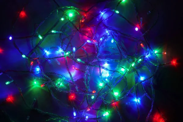 Lumières multicolores de Noël. Les lumières LED électriques sont disposées au hasard sur un fond sombre. Guirlande décorative. Gros plan — Photo