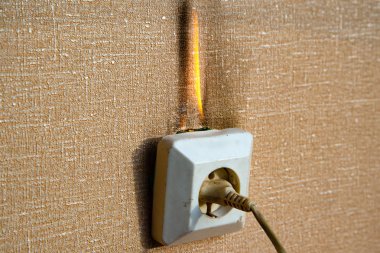Yanan elektrik kabloları ve elektrik prizi. Hatalı kablolama yangına neden olur. Kötü eski kablolama elektrik prizinde yangına neden olur.