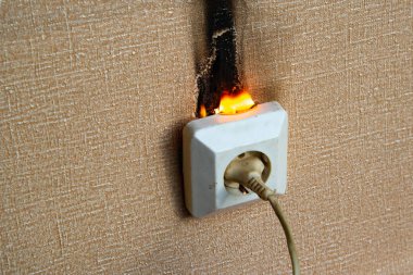 Yanan elektrik kabloları ve elektrik prizi. Hatalı kablolama yangına neden olur. Kötü eski kablolama elektrik prizinde yangına neden olur.