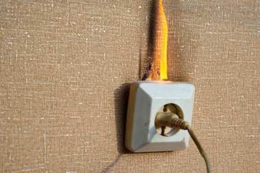 Yanan elektrik kabloları ve elektrik prizi. Hatalı kablolama yangına neden olur. Kötü eski kablolama elektrik prizinde yangına neden olur.