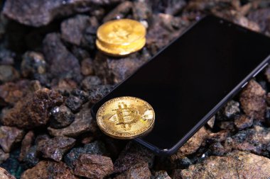 Akıllı telefon ve bitcoinler. Bitcoin paraları akıllı telefonun ekranının yanında. Para birimi büyümesinin akıllı telefon ekran grafiğinde