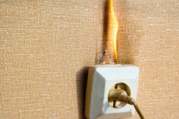 Burning electrical wiring and electrical outlet. Faulty wiring causes fires. Poor old wiring causes a fire in the electrical outlet. — Stock Photo, Image