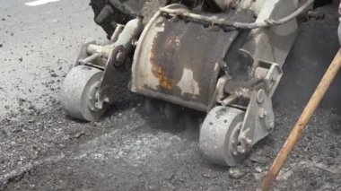 Yol frezeleme makinesi eski asfalt keser. Yol tamiri. Yol yüzeyinin yok edilmesi. Kesici bir asfalt tabakası keser. Taş parçaları birbirinden ayrı uçar. Close