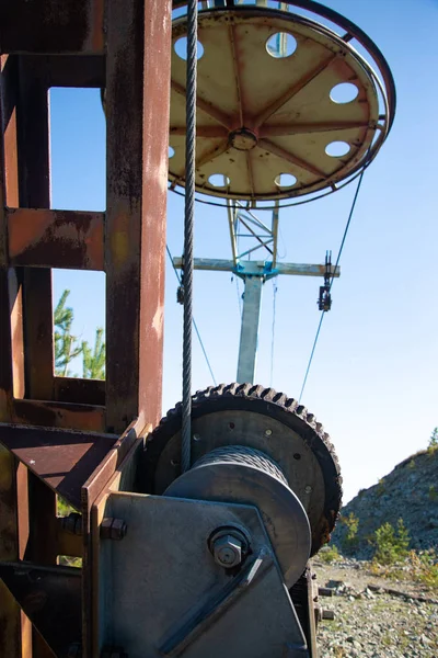 Steel cable and winch. Part of an old winch with a steel rope on a lift. Detail of the cableway. Close-up view of steel big wheel of cableway in mountains against the blue sky.