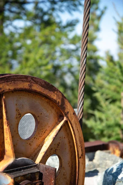 Steel cable and winch. Part of an old winch with a steel rope on a lift. Detail of the cableway. Close-up view of steel big wheel of cableway in mountains against the blue sky.