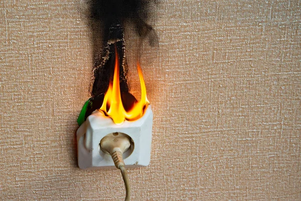 Yanan elektrik kabloları ve elektrik prizi. Hatalı kablolama yangına neden olur. Kötü eski kablolama elektrik prizinde yangına neden olur.