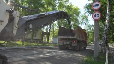 Chelyabinsk Bölgesi, Rusya - Temmuz 2019. Chelyabinsk Bölgesi, Rusya - Temmuz 2019. Yol tamiri. Bir yol değirmeni makinası eski asfaltı keser ve bir çöp kamyonuna yükler. Devamlı görev döngüsü.