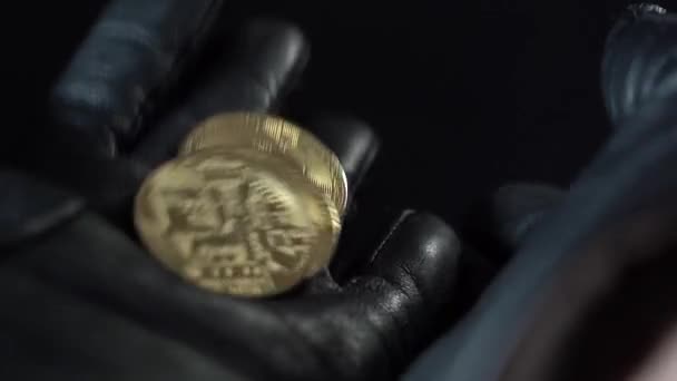 Munten Bitcoins close-up. Giet van palm naar palm. Donkere achtergrond. Zwarte leren handschoenen op de handen. — Stockvideo