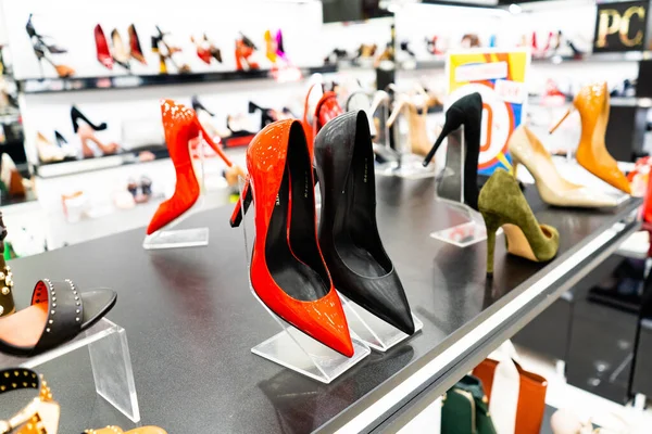 Chelyabinsk Region, Rusia - Agustus 2019. Sepatu hak tinggi merah. Jajaran sepatu wanita cantik, elegan, berwarna di rak toko. Toko sepatu wanita Stok Lukisan  