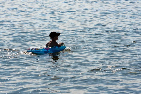 O rapaz nada no lago. Em torno de um monte de spray e espuma. Uma criança nada no lago . — Fotografia de Stock
