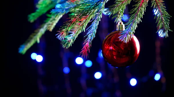 Closeup of a red ball on a christmas tree. Multi-colored bokeh — Stock Photo, Image