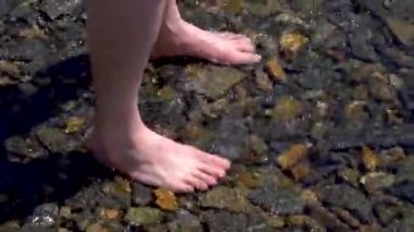 Erkeğin ayakları dalgaların yumuşak dalgalarıyla yıkanır..